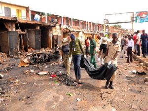 Rescuers carry a body recovered from a burnt shop at the scene of twin bomb blasts at terminus market  in the central city of Jos on May 21, 2014.  Twin car bombings in central Nigeria killed at least 118 people and brought entire buildings down Tuesday, in the latest affront to the government's internationally-backed security crackdown. Nigerian President Goodluck Jonathan swiftly condemned the attack in the central city of Jos, calling it a "tragic assault on human freedom" and condemning the perpetrators as "cruel and evil". AFP PHOTO/  STR